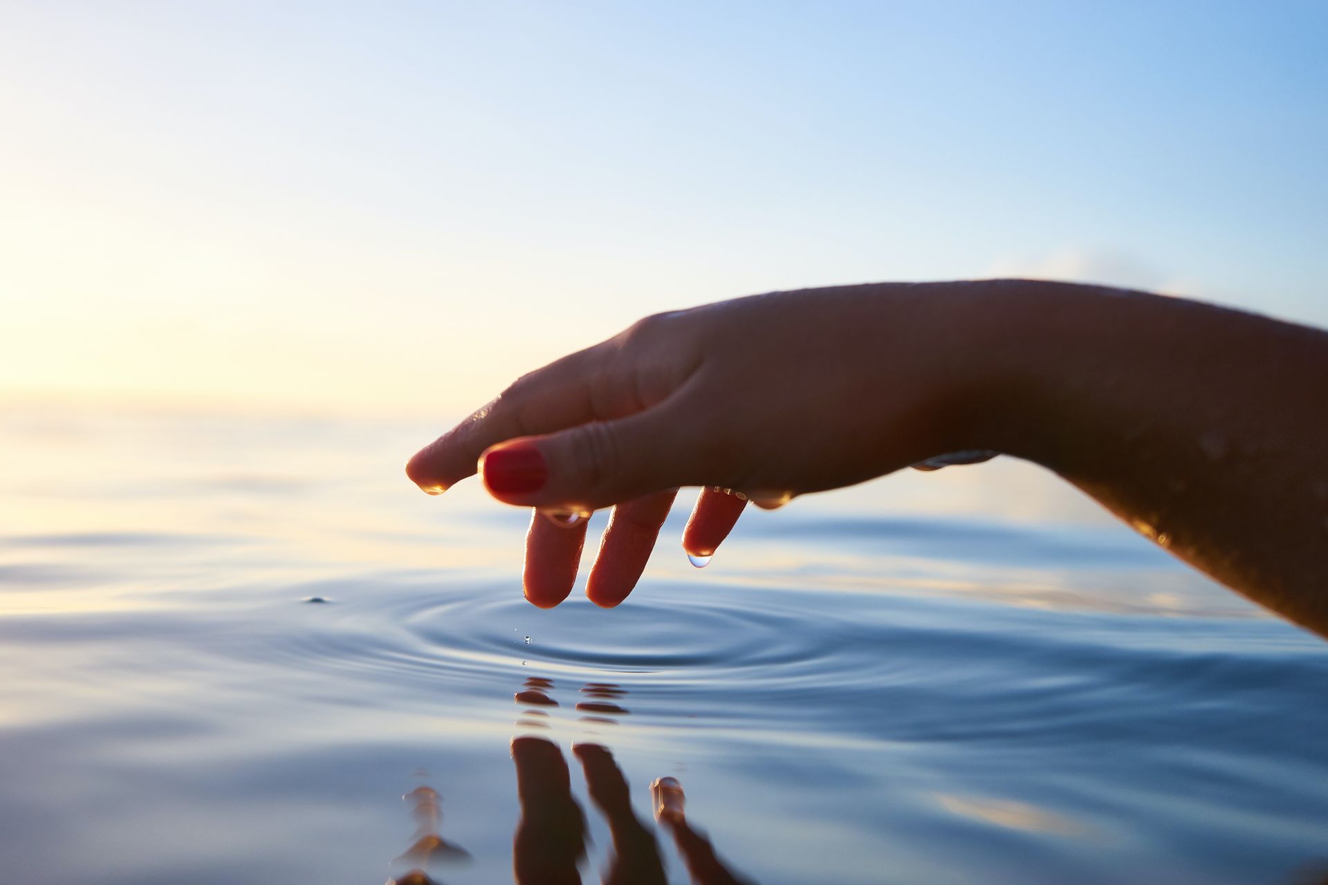 A hand touching the surface of still water
